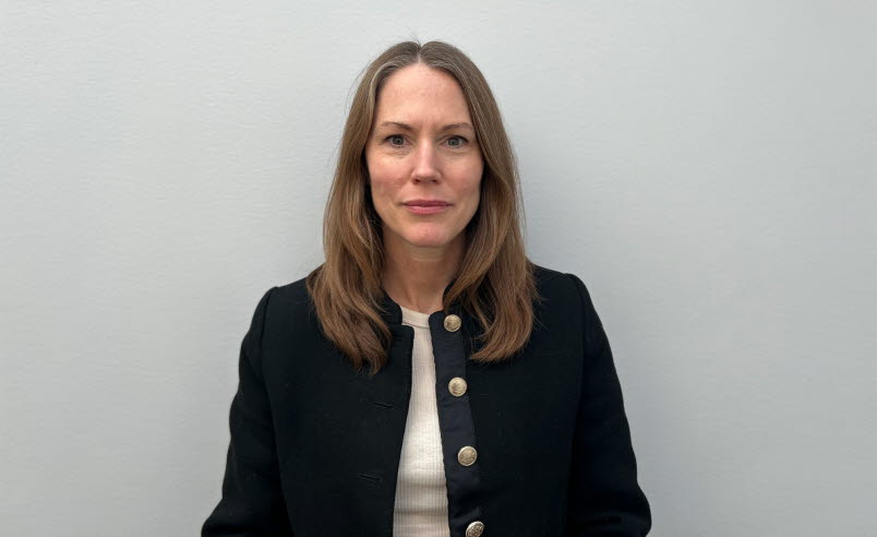 Woman in black cardigan, white t-shirt and brown hair.