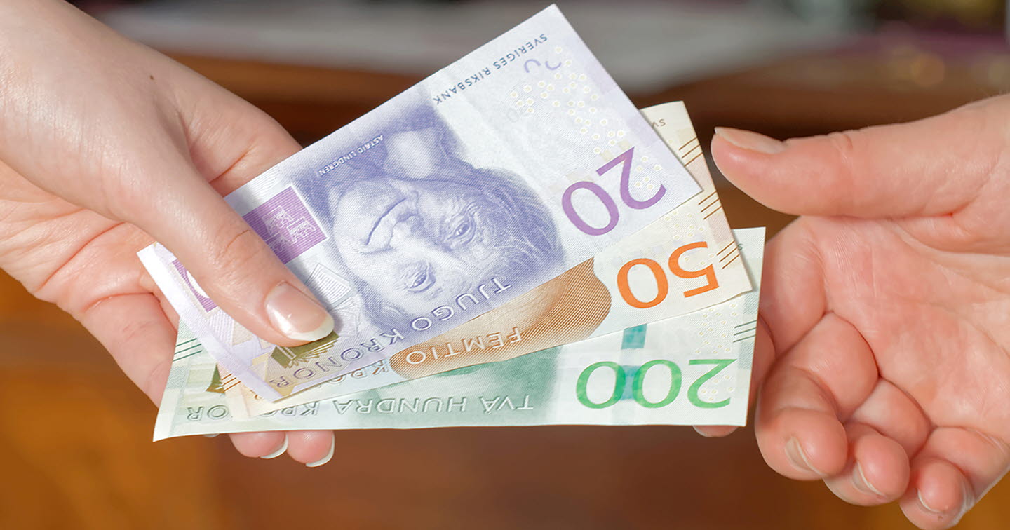 En hand som överlämnar svenska kontanter